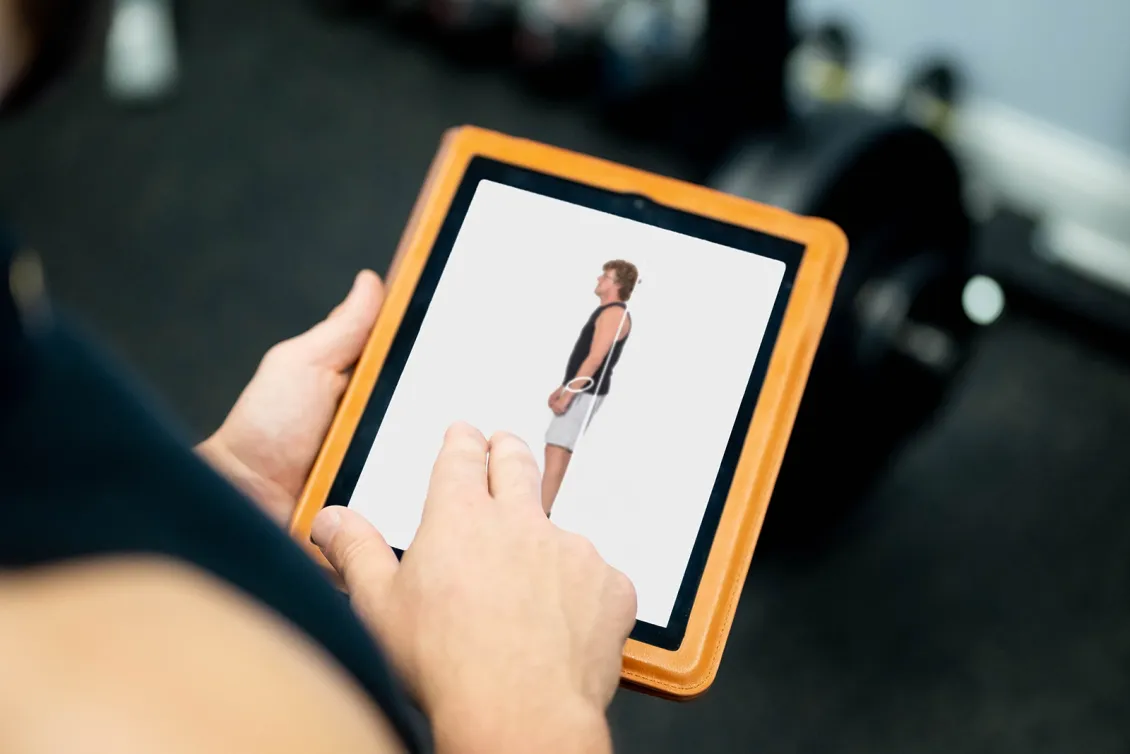 Biomechanics specialist holding a tablet displaying an image of a clients imbalances.