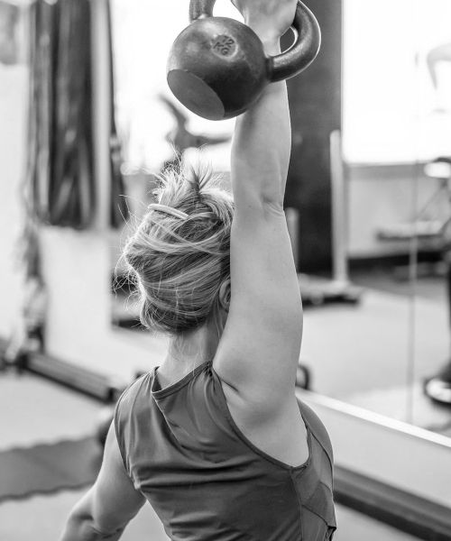 UPLIFT fitness class member overhead kettlebell press