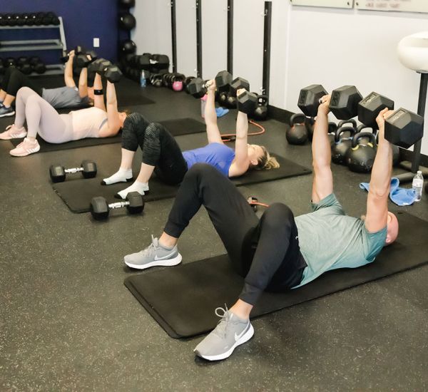 UPLIFT fitness class members performing a floor press