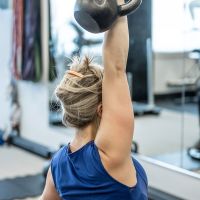 UPLIFT fitness class member overhead kettlebell press