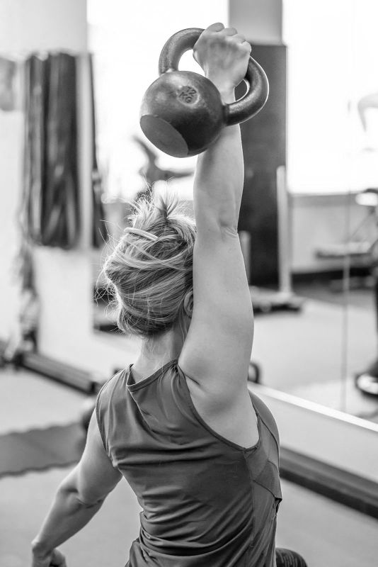 UPLIFT fitness class member overhead kettlebell press