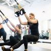 UPLIFT fitness class members performing a TRX pistol squat