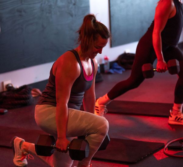 UPLIFT fitness class member performing stepback lunge with dumbells