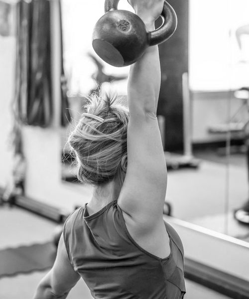 UPLIFT fitness class member overhead kettlebell press